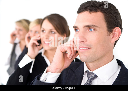 A businessman and three businesswomen out of focus behind him all talking on cell phones Stock Photo