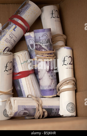 wads of 20 pounds sterling bank of england notes cash tied up in a rolls with elastic band hidden in a cardboard box Stock Photo
