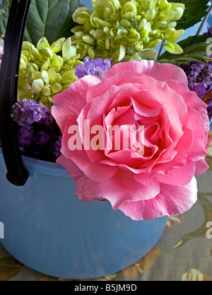 Blue bucket of flowers, including pink rose, hydrangeas and lavender. Stock Photo
