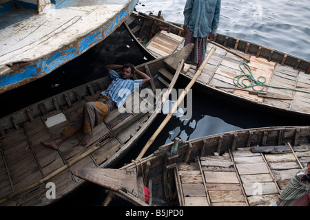 A man relaxing in a boat on the Buriganga River in Dhaka Bangladesh Stock Photo