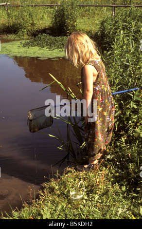 Young girl with fishing net beside pond Stock Photo