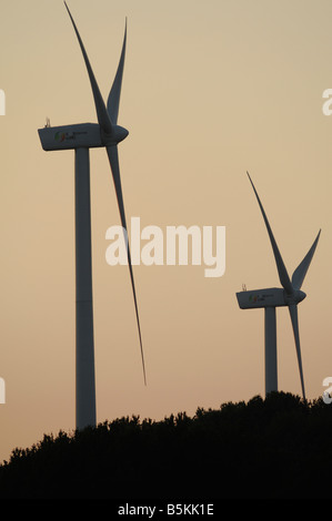Wind turbines at a wind farm with the silhouettes of two girls ...