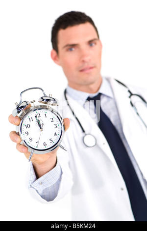 A male doctor holding out an alarm clock ticking ever closer to 12 o clock The focus is on the clock face