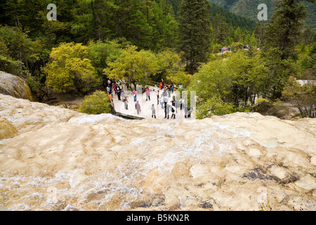 Tourists on viewing platform at foot of travertine calcified Golden Flying Waterfall in Huanglong Sichuan Province China JMH3525 Stock Photo