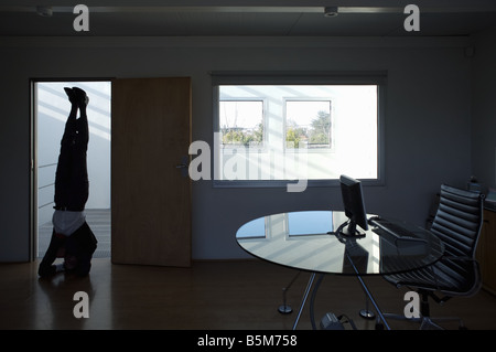 Businessman practicing yoga at office Stock Photo