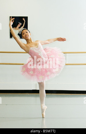 A ballerina in a pink tutu in an arabesque pose. Stock Photo