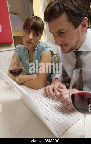 A bored woman looking at a man using a laptop. Stock Photo