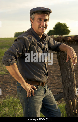 A man on a ranch leaning on a fence post