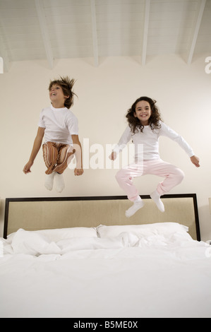 A boy and a girl jumping on a bed Stock Photo