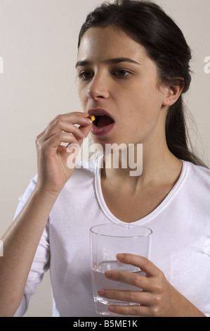 A woman putting a pill into her mouth Stock Photo