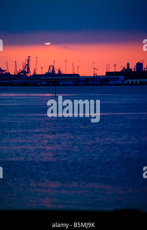 the river Thames at sunset seen from Gravesend with the cranes of Tilbury silhouetted in background Stock Photo