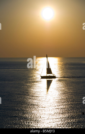 A sailboat navigating in the water with sunlight. Stock Photo