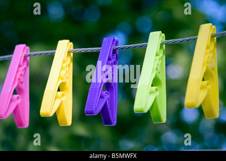 Brightly coloured pegs hanging on a washing line. Stock Photo