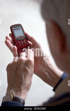 Elderly man using mobile phone to send text message Stock Photo