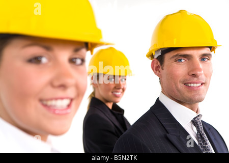 A selective focus industrial concept shot showing 2 women and a man dressed in hard hats, focus is on the man on the right Stock Photo