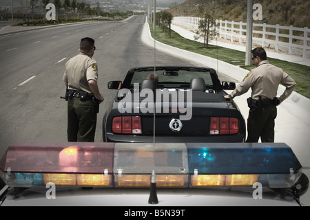 Two police officers approaching man driving Mustang Stock Photo