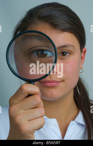 Young teenager looking through a magnifying glass Stock Photo