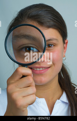 Young teenager looking through a magnifying glass Stock Photo