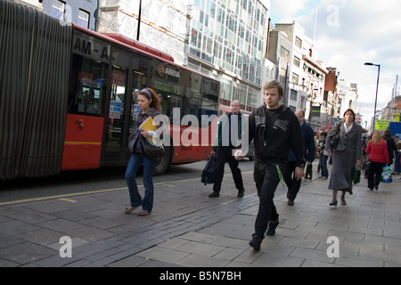 People walking past a 'bendy bus' in Oxford Street, in central London, UK Stock Photo