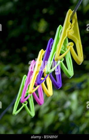 Side view of brightly coloured pegs hanging on a washing line. Stock Photo