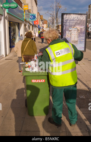 Waveney District Council worker clearing up litter and filling wheelie bin in the streets of Lowestoft,Suffolk,Uk Stock Photo