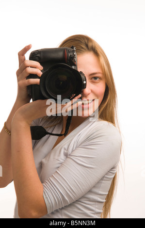 A Young blonde woman photographer using an expensive Nikon digital SLR DSLR camera taking photographs in studio Stock Photo