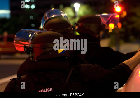 Police officers wearing riot helmets and equipment ride though downtown Denver Colorado Democratic National Convention Stock Photo