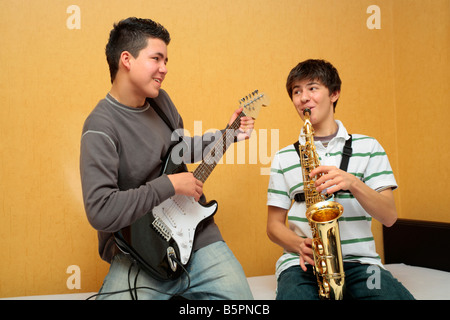 two teenage boys playing the electric guitar and the saxophone together Stock Photo