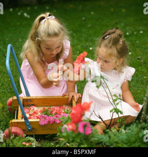 Pretty young girls playing in the garden collecting flowers Stock Photo