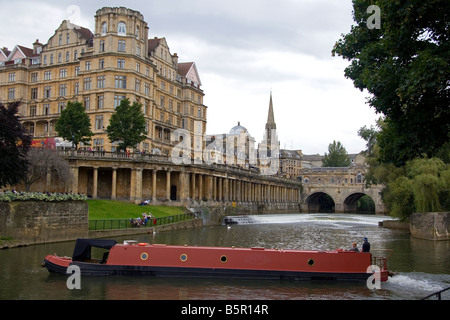 A narrowboat on the River Avon in front of the Pulteney Bridge and Abbey Hotel in the city of Bath Somerset England
