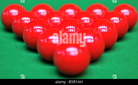A perfectly racked triangle of snooker, red billiard balls, reflecting the skylight on the green felt of the pool table. Stock Photo