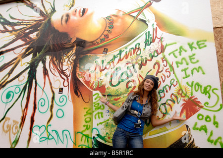 A model poses infront of a massive poster celebrating London's Notting Hill Carnival Stock Photo