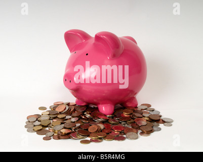 side profile of a pink piggy bank sitting on a pile of coins Stock Photo