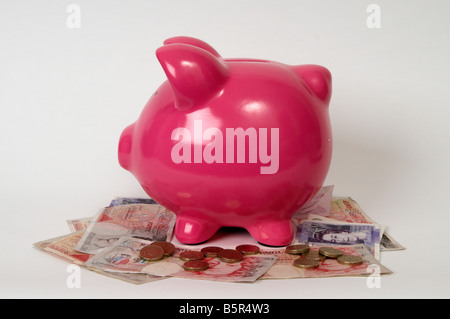 Pink piggy bank sitting on a pile of British Pounds bank notes Stock Photo