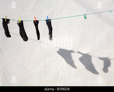 A washing line and clothes pegs with socks hung out to dry and shadows in the sunshine at Fethiye, Turkey Stock Photo
