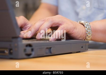 A young man typing on a laptop computer keyboard Stock Photo
