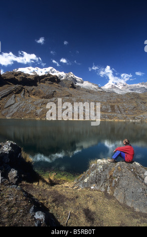 Trekker looking at view across Lake Chillata, Mts Illampu and Ancohuma in background, Cordillera Real, Bolivia Stock Photo