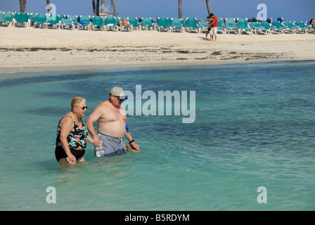 A mature couple venture into the ocean together holding hands at Little Stirrup Cay, Bahamas. Stock Photo