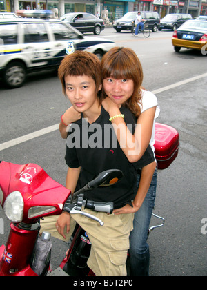 A young Chinese couple on a scooter smile in Beijing China Stock Photo