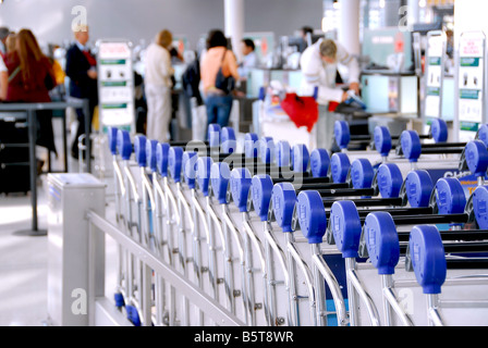 Luggage carts at modern international airport passengers at check in counter in the background Stock Photo