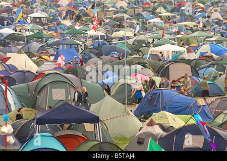 Glastonbury Festival fans and festival goers walk through the busy hectic tent camping area scene at Glastonbury June 2008 Stock Photo