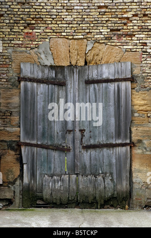 An old derelict wooden door set in weathered brick wall Stock Photo
