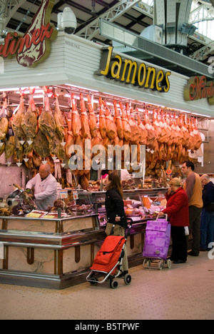 Spanish people shopping at a meat stall in the central market Mercado Central in the historical city centre of Valencia Spain Stock Photo