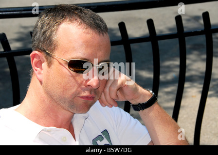 Portrait of a thoughtful man wearing sunglasses in outdoor cafe Stock Photo