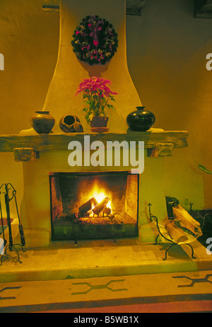 adobe fireplace decorated with Indian pottery and flowers on Christmas Eve Santa Fe New Mexico United States of America USA Stock Photo