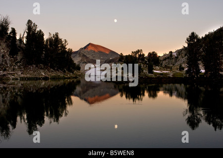 Sentinel Peak and a nearly full moon are reflected in the waters of Glacier Lake Eagle Cap Wilderness Wallowa Mountains Oregon Stock Photo