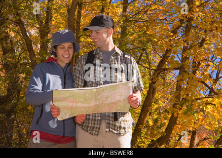 Young couple consulting a map while hiking amid the autumn colors on the Temple Quarry Trail in Little Cottonwood Canyon Wasatch Stock Photo