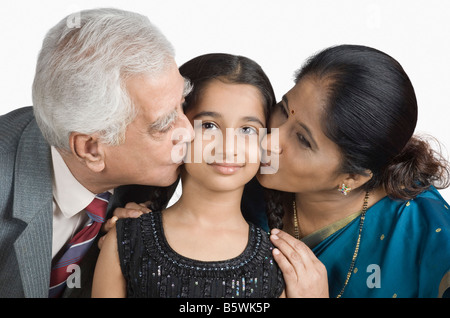 Senior man and a mature woman kissing their granddaughter Stock Photo