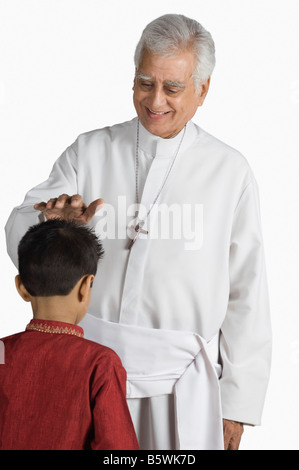 Priest blessing a boy and smiling Stock Photo