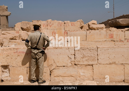 An Egyptian policeman looking at fragments of hieroglyphs in Temple of Ramses II in Abydos one of the oldest cities of ancient Egypt Stock Photo